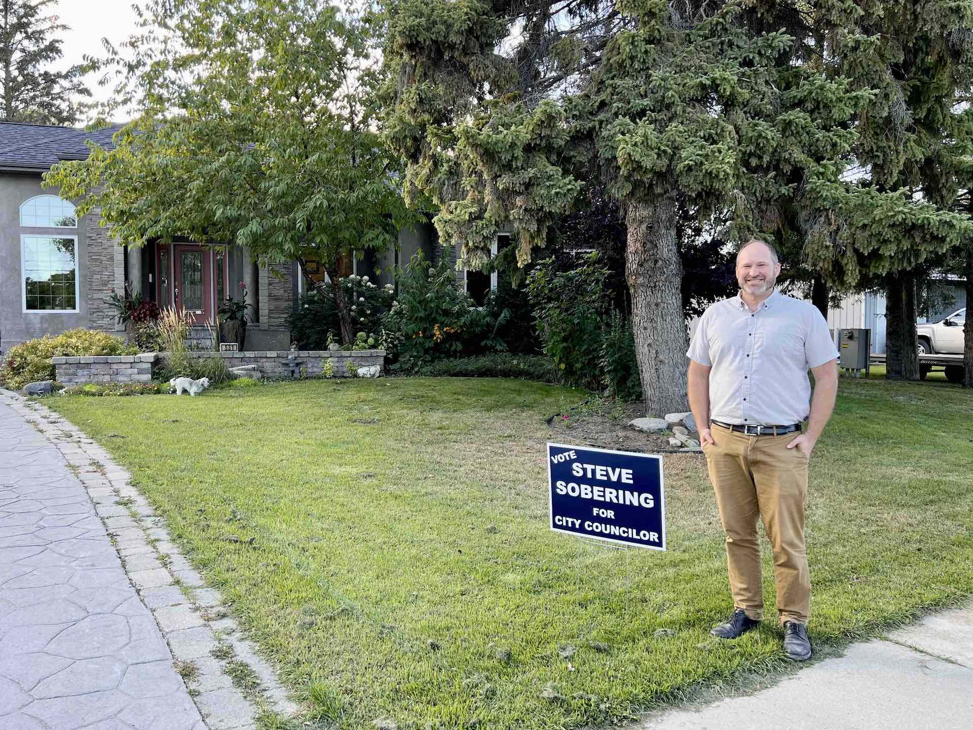 Photograph of Steve Sobering beside campaign sign