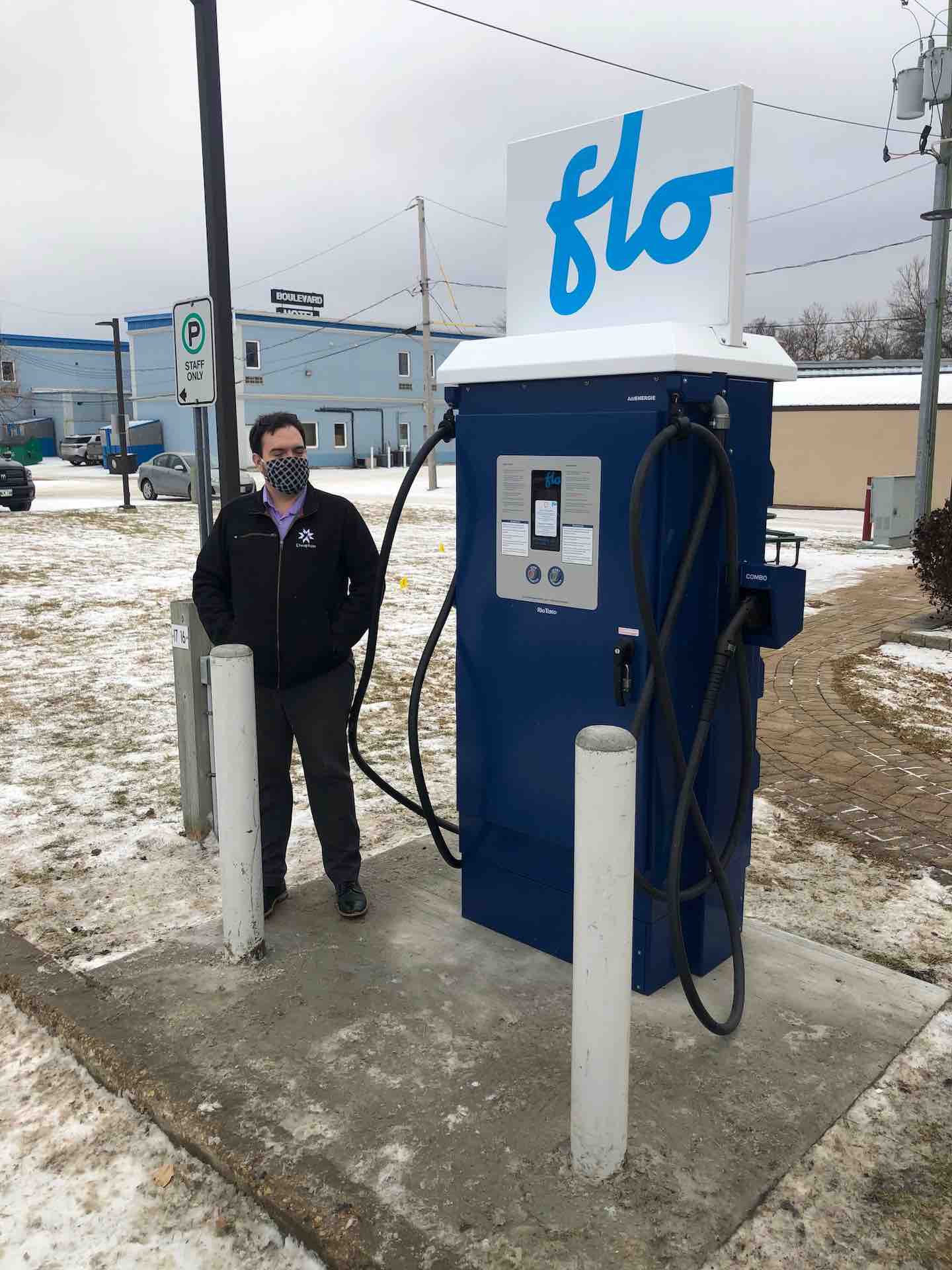 Photograph of person standing next to electric vehicle charger.